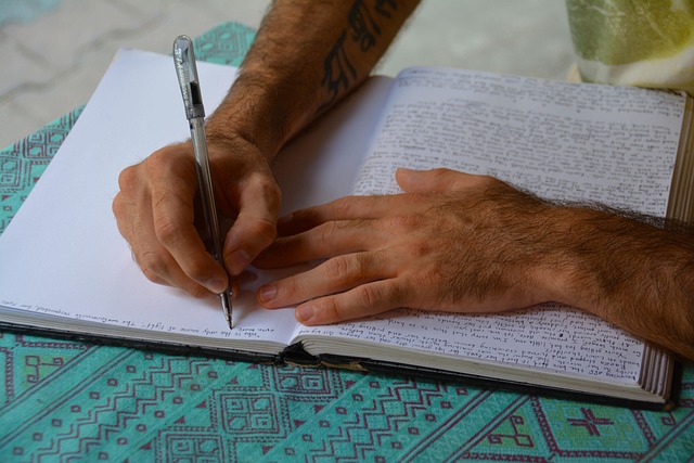 A person writing in a notebook with a pen