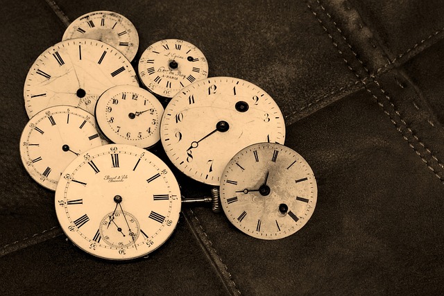 Multiple vintage clock and pocket watch faces on a dark surface