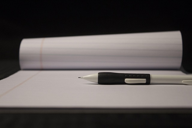 A mechanical pencil lying on an open lined notepad