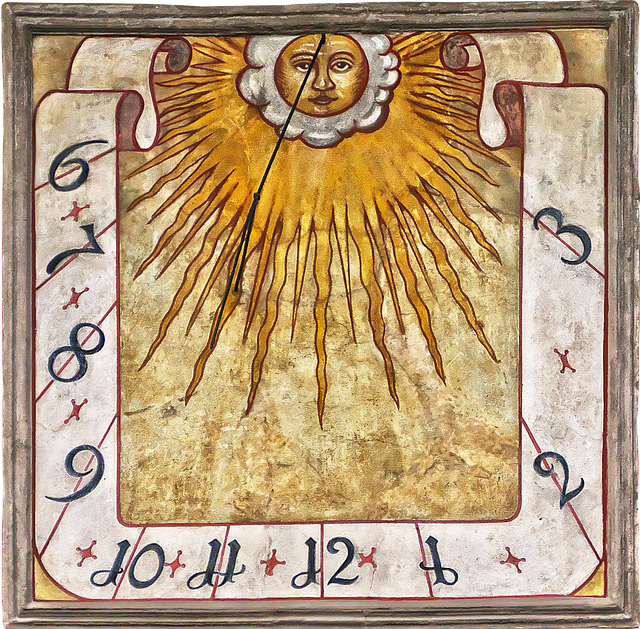 An artistic painted vertical sundial with a stylized sun face