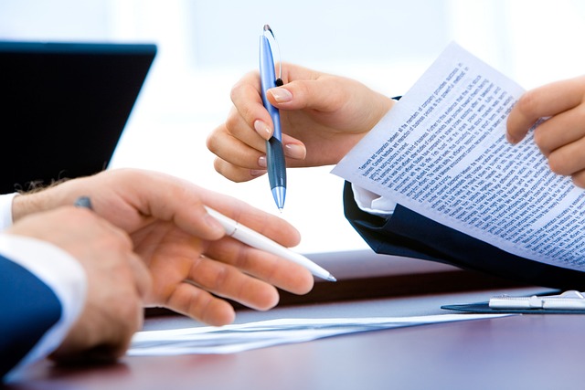 Business people holding pens and reviewing a printed document at a desk
