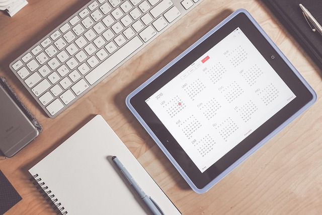 A tablet displaying a yearly calendar on a wooden desk