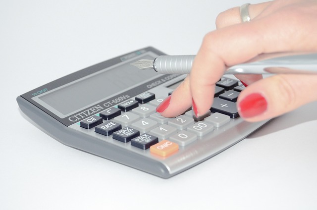 A person using a calculator while holding a fountain pen