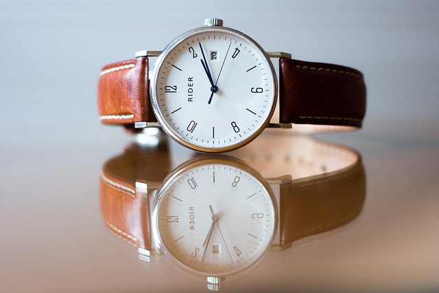 An analog wristwatch resting on a reflective surface